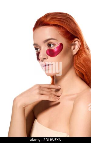 Eine atemberaubende Frau mit leuchtend roten Haaren posiert elegant in Augenpartien und zeigt moderne Schönheit. Stockfoto