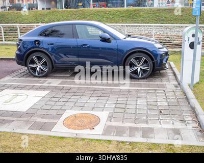 Cremona, Italien 9. Januar 2026 Porsche Macan 4 Electric SUV, Modell 2024, Aufladen an einer Außenstation, Symbol für nachhaltigen Transport und Zukunft Stockfoto
