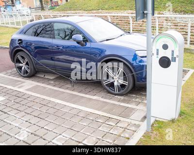 Cremona, Italien 9. Januar 2026 Blauer Porsche Cayenne E Hybrid-SUV, der seine Batterie an einer EV-Station auflädt, zeigt Elektromobilität, Nachhaltigkeit, A Stockfoto