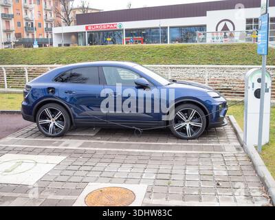 Cremona, Italien 9. Januar 2026 Porsche Macan 4 Electric SUV, Modell 2024, Aufladen an einer Außenstation, Symbol für nachhaltigen Transport und Zukunft Stockfoto