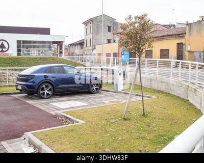 Cremona, Italien 9. Januar 2026 Porsche Macan 4 Electric SUV, Modell 2024, Aufladen an einer Außenstation, Symbol für nachhaltigen Transport und Zukunft Stockfoto