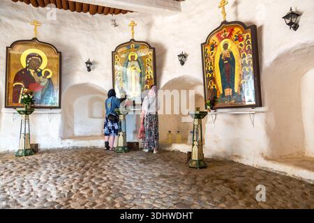 Pechory, Russland - 30. August 2024: Pilger im Kloster Pskowo-Petscherski (Pskov-Höhlen) neben den alten orthodoxen Ikonen Stockfoto