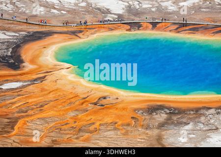 Farbenfrohe Grand Prismatic Spring im Midway Geyser Basin von Yellowstone mit lebhaften Regenbogenfarben und Touristen auf der Promenade. Stockfoto