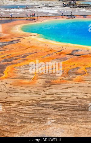 Farbenfrohe Grand Prismatic Spring im Midway Geyser Basin von Yellowstone mit lebhaften Regenbogenfarben und Touristen auf der Promenade. Stockfoto