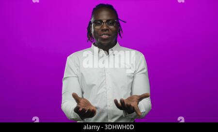 Mann mit offenen Handflächen und lächelnder Geste im Studio mit magentafarbenem Hintergrund, mit weißem Hemd und Brille; Vertrauensverbindung. Stockfoto