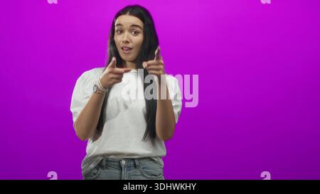 Die Frau zeigt mit dem Finger auf die Kamera und trägt im Studio ein weißes Hemd und eine Jeans. Stockfoto