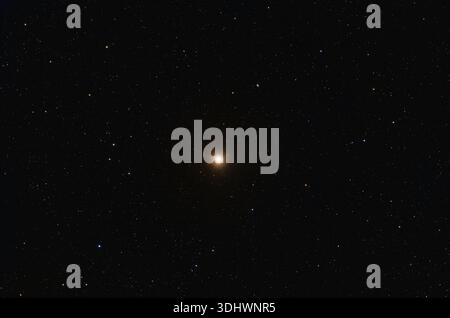 Betelgeuse-Stern im Sternbild Orion, strahlend gelbes Licht auf dunklen Nachthimmel. Stockfoto