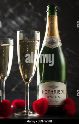 Champagnerflasche und gefüllte Gläser mit rotem Herzdekor, auf dunklem Hintergrund Stockfoto