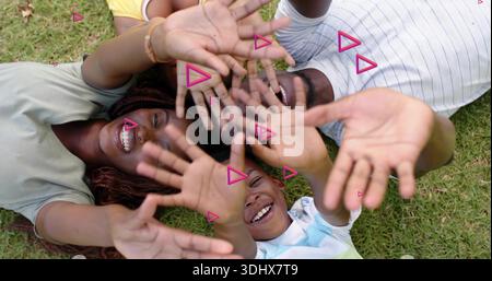 Mit T-Shirts und Poloshirts, pinken Überzügen, erreichen Sie eine vierköpfige Familie auf dem Rasen und heben die Hände zur Kamera Stockfoto