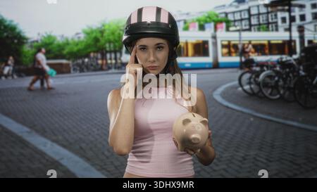 Frau auf der Straße, die Schweinebank hält und mit dem Finger auf den Tempel zeigt, während sie einen rosafarbenen Helm vor Straßenbahn und Fahrradständer trägt; Entschlossenheit. Stockfoto