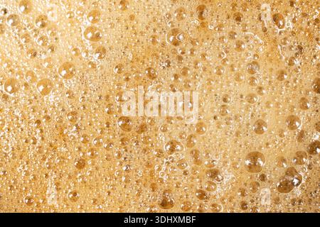 Abstrakter Hintergrund der Espresso-Crema mit Luftblasen-Nahaufnahme. Stockfoto