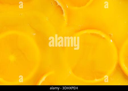 Abstrakter Hintergrund von Orangenscheiben, die mit dickem Saft bedeckt sind. Stockfoto