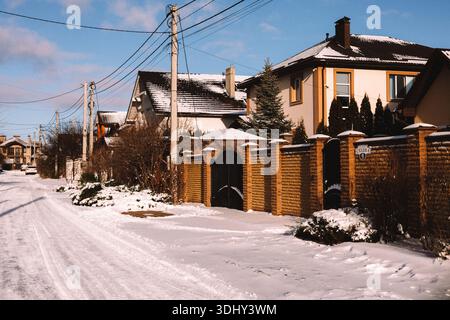 KIEW, Ukraine 13. Dezember 2025 Filmaufnahme eines modernen Backsteinhauses hinter einem hohen Backsteinzaun an einem sonnigen Wintertag. Schneebedeckte Gärten mit do Stockfoto