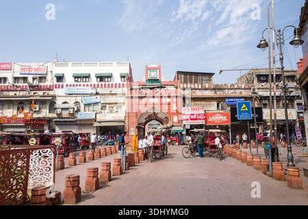 Delhi, Indien - 29. März 2024: Das östliche Eingangstor von Fatehpuri Masjid ist sichtbar mit Menschen, die zu Fuß gehen, mit dem Fahrrad Rikschas fahren, und umliegenden Geschäftsgebäuden mit Ladenschildern und Straßenverkäufern. Stockfoto