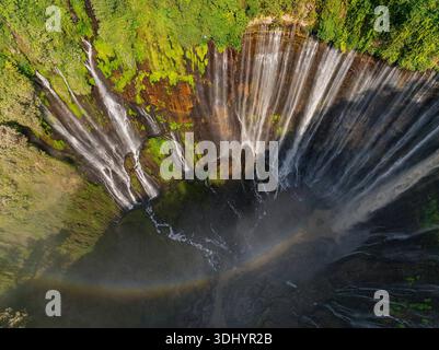 Blick von oben auf den Tumpak Sewu Wasserfall mit Regenbogen im üppigen tropischen Wald, Indonesien Stockfoto