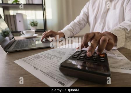 Vorbereitung der Einkommensteuererklärung mit dem Rechner 1040 Formulare, Geschäftsmann, der am Laptop arbeitet, um Abzüge zu berechnen, Ausgaben zu verwalten, Steuerbudget zu planen Stockfoto