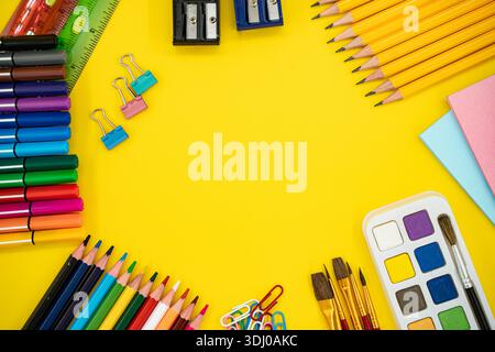 Flache Lage von bunten Schul- und Kunstbedarf auf gelbem Hintergrund mit Kopierraum. Stockfoto