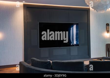 Luxuriöses Wohnzimmer mit wandmontiertem Fernseher und kundenspezifischer Medienwand aus Holzkohle Stockfoto