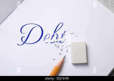 Löschen von Wort Schulden in Notizbuch auf Tabelle, Draufsicht Stockfoto