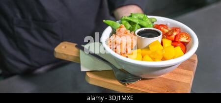 Nahaufnahme eines nicht erkennbaren Küchenchefs, der frisch bunte Poke Bowl mit Lachs in der Restaurantküche zeigt Stockfoto