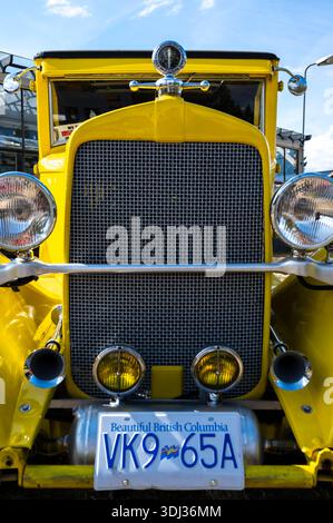 Die Nahaufnahme des Kühlergrills und der Scheinwerfer eines alten gelben Hot Rods unterstreicht die Chromdetails, runden Lichter und den unverwechselbaren Retro-Stil Stockfoto