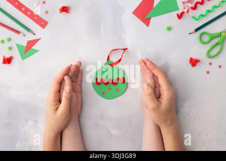 Das Kind macht eine Weihnachtsdekoration aus Papier. Mit seinen eigenen Händen gemacht. Schritt-für-Schritt-Anleitung. Kinderkunstwerk für Kinder. Basteln für Chil Stockfoto