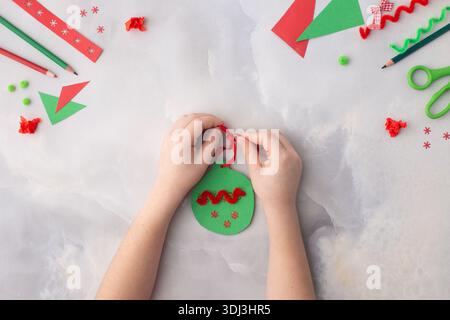 Das Kind macht eine Weihnachtsdekoration aus Papier. Mit seinen eigenen Händen gemacht. Schritt-für-Schritt-Anleitung. Kinderkunstwerk für Kinder. Basteln für Chil Stockfoto