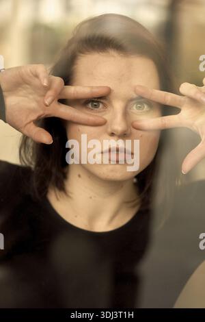 Eine Frau gibt spielerisch mit ihren Händen um ihre Augen, zeigt ihre Augen durch Reflexion, Visionär, Sehvermögen, Sehen, Sehen, Sehen, Idee, Messung Stockfoto