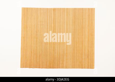 Ein kleines Tischset aus Bambusstöcken auf einer weißen Oberfläche Stockfoto