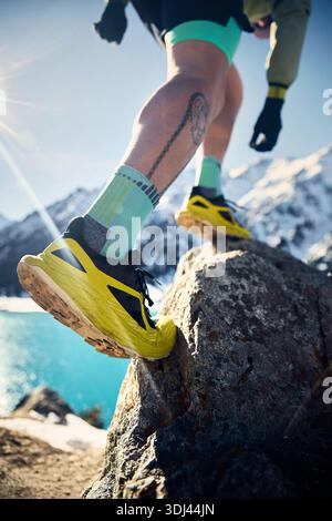 Nahaufnahme von Laufschuhen des Mannes Athlet Runner auf dem Stein im Bergtal am sonnigen Wintertag. Joggen in Sportbekleidung in der Natur. Stockfoto