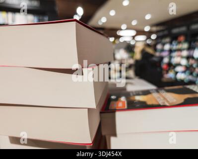 Bücherstapel in einem Buchladen umgeben von verschwommenen Regalen, Literatur, Buchhandlung, Köln, Nordrhein-Westfalen, Deutschland Stockfoto