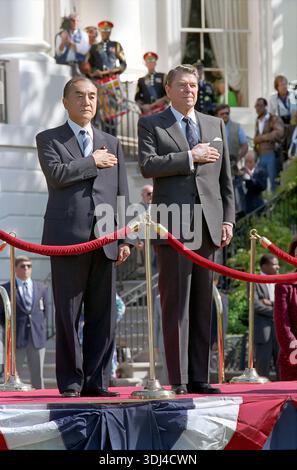 US-Präsident Ronald Reagan und Premierminister Yasuhiro Nakasone aus Japan hören während eines Staatsbesuchs Nationalhymnen auf dem Südrasen des Weißen Hauses, Washington, D.C., USA, Präsident Ronald Reagan, Fotobüro des Weißen Hauses, 30. April 1987 Stockfoto