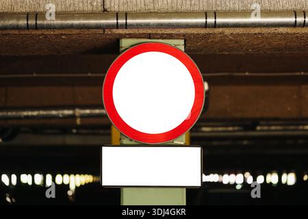 Warnschild für Tiefgarage. Leeres kreisförmiges Verkehrsschild in Innenräumen. Leeres Symbol auf rotem Rahmen. Innenbeleuchtung in der Garage. Städtische Infrastruktur. Stockfoto