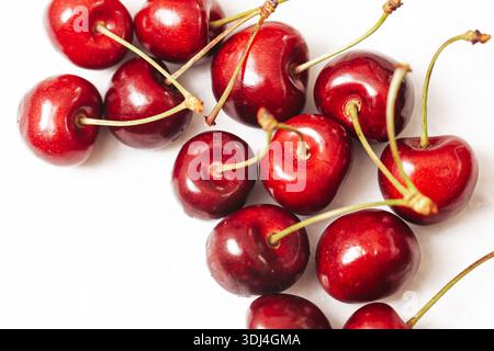 Frische Kirschen auf weißem Hintergrund. Rote reife Früchte mit Stielen. Gesunde Snack-Zutat zum Dessert. Sommerernte Nahaufnahme mit Kopierraum. Stockfoto