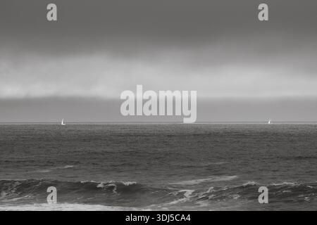 Schwarz-weißes Meer und Segelboot am Horizont. Stockfoto