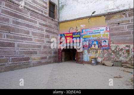 Prayagraj, Indien - 21. März 2024: Das Bild zeigt das Eingangstor des Fort Akbar mit großen Hindi-Schildern und Plakaten über dem Torbogen, flankiert von Steinmauern und einem Mülleimer auf der rechten Seite. Stockfoto