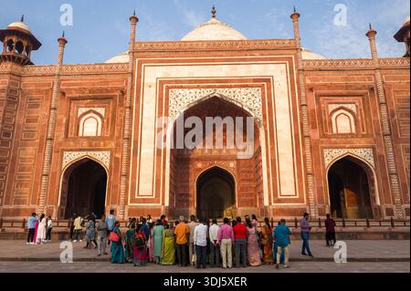 Agra, Indien - 11. März 2024: Eine Gruppe von Menschen steht im vorderen Innenhof gegenüber der Hauptfassade der Jawab-Masjid-Moschee am Taj Mahal-Komplex, mit roter Sandsteinarchitektur mit weißer Marmoreinlage und bogenförmigen Eingängen unter klarem Himmel. Stockfoto