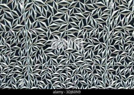 Ein Schwarzweißfoto einer gemusterten Wand mit weißen und schwarzen Formen. Das Foto hat eine moderne und minimalistische Atmosphäre Stockfoto