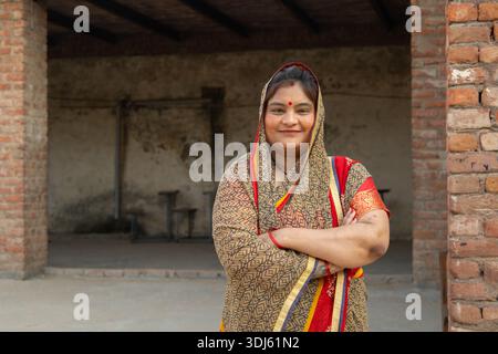 Selbstbewusste Indianerin, die im Freien steht und traditionelle Saree-Arme überkreuzt trägt. Ländliches indien Stockfoto