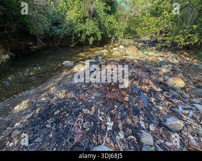 Pampanga, Philippinen. Januar 2026. Verbrannter Sperrmüll sammelt sich in einem ausgetrockneten Flussbett an. Haushaltsgegenstände und mechanische Gegenstände wurden vor Ort entsorgt und verbrannt, wobei nur verdrehte und oxidierte Metallteile zwischen Steinen und Asche verstreut blieben. Solche informellen Dumpingpraktiken bestehen in vielen Teilen des philippinischen Archipels weiter, wo die Bewohner davon ausgehen, dass saisonale Regenfälle die verbleibenden Trümmer flussabwärts waschen. Die Philippinen gehören zu den weltweit größten Beiträgen zur Verschmutzung von Plastik und Abfällen im Meer, wobei Flüsse als Hauptwege dienen, die Schutt in den Ozean transportieren.Quelle: Kevin Izorce/Alamy Live News Stockfoto