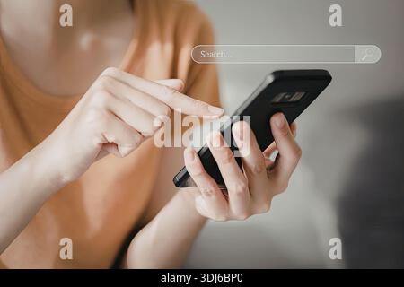 Ein Nahbild einer Person, die ein Smartphone verwendet, um eine Suche durchzuführen. Der Fokus liegt auf den Händen und dem Smartphone-Bildschirm, auf dem eine Suchleiste angezeigt wird. Stockfoto