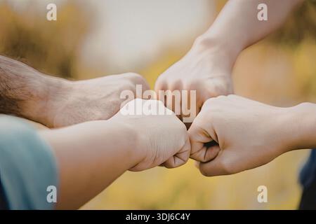 Ein Bild, das eine Gruppe von Menschen zeigt, die sich an einem feierlichen Faustschlag beteiligen und Teamarbeit, Einheit und Kameradschaft symbolisiert. Stockfoto
