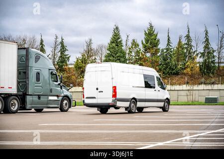 Grau-Lkw-Sattelzugmaschine in Industriequalität mit hohem Fahrerhausprofil und Kühlschrank mit Auflieger und Cargo-Minivan auf dem markierten Parkplatz Stockfoto