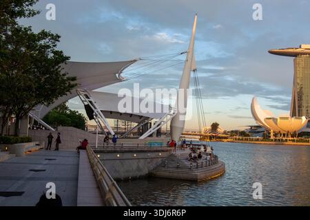 Eine moderne architektonische Struktur am Wasser mit großen weißen Segeln und einem schlanken Design, mit Leuten sitzen und die Aussicht genießen Stockfoto