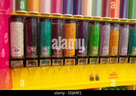 Eine farbenfrohe Ausstellung von Süßigkeitenspendern gefüllt mit verschiedenen Süßigkeiten, einschließlich Schokolade und überzogene Süßigkeiten, in einer lebendigen Umgebung Stockfoto