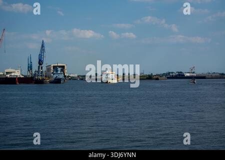 Ein Blick auf einen Hafen mit verschiedenen Schiffen und Kränen, unter einem blauen Himmel mit verstreuten Wolken Stockfoto