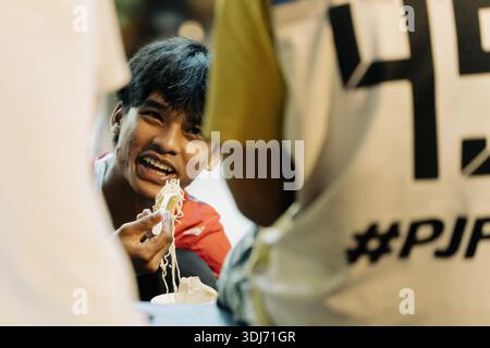 Khao Lak, Thailand, 24 11 2025: Candid Moment of Thai Youth Genießen von Street Food auf dem Nachtmarkt Stockfoto