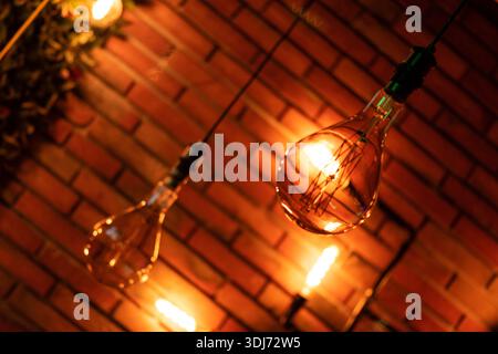 Glühlampen beleuchten das Café mit Ziegelsteinen und Pflanzen im Inneren Stockfoto