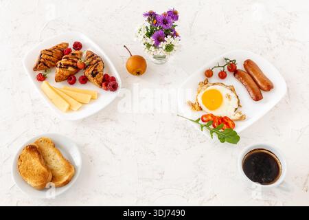 Spiegelei und gegrillte Würstchen, serviert mit frischen Tomaten und Paprika. Stockfoto