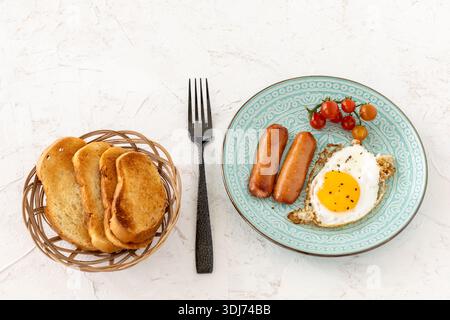 Spiegelei und gegrillte Würstchen mit frischen Tomaten auf dem Teller. Stockfoto